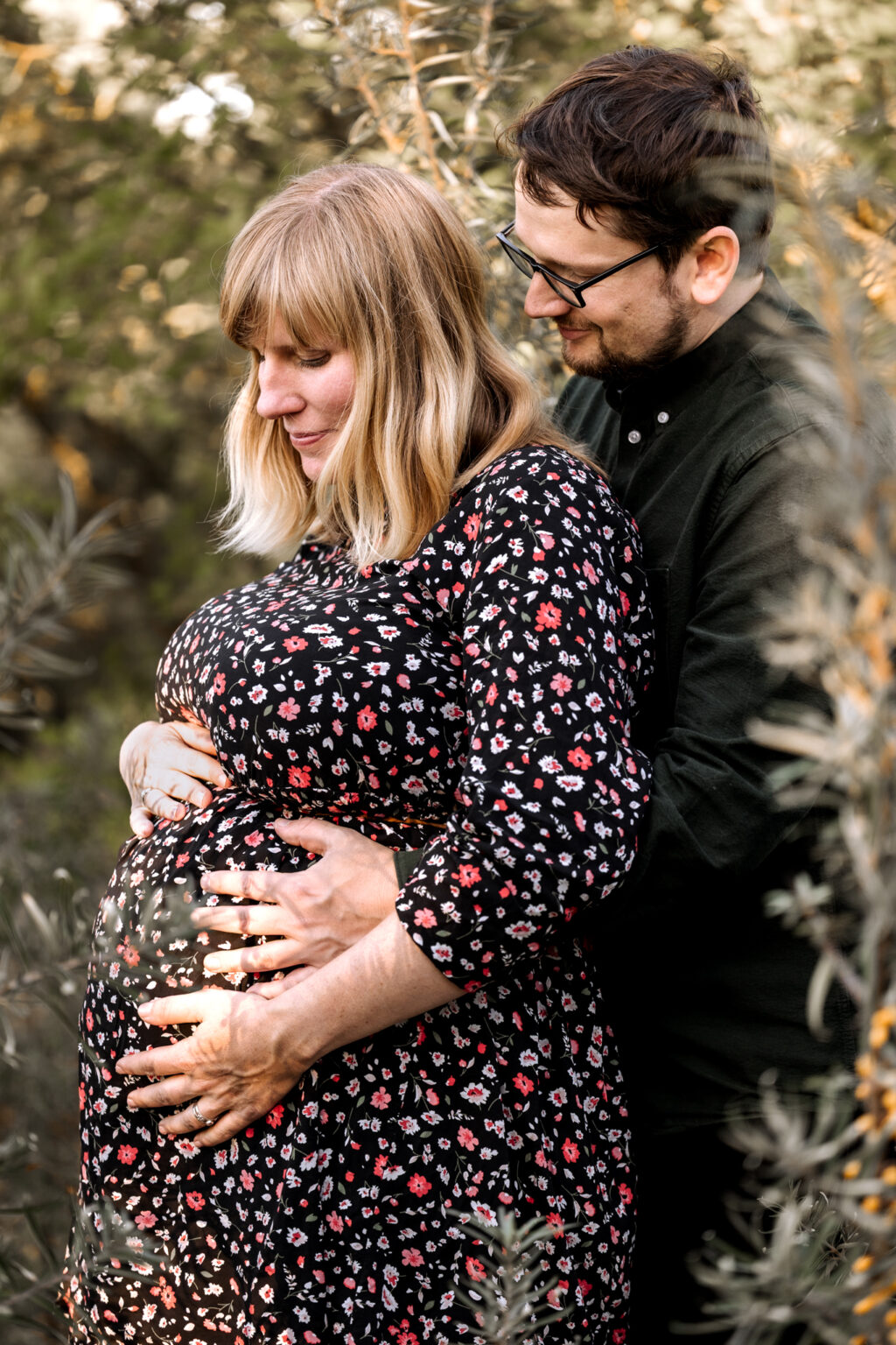 Ein Paar hält sich liebevoll in den Armen bei einem Schwangerschaftsshooting im Grünen – Pure Portraits Leipzig