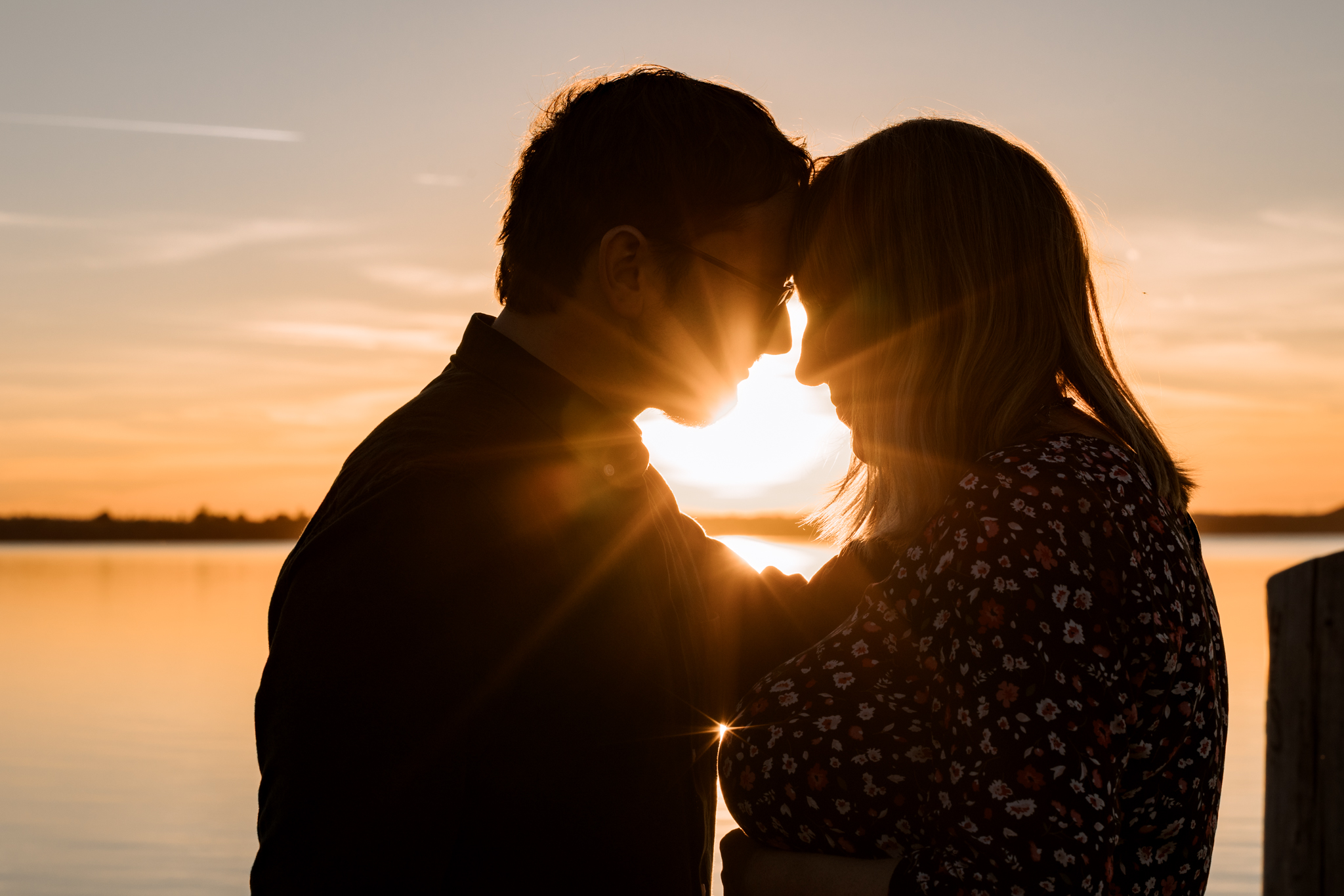 Paarfotografie im Abendlicht – Schwangerschaftsshooting am See bei Leipzig mit Sonne im Hintergrund.